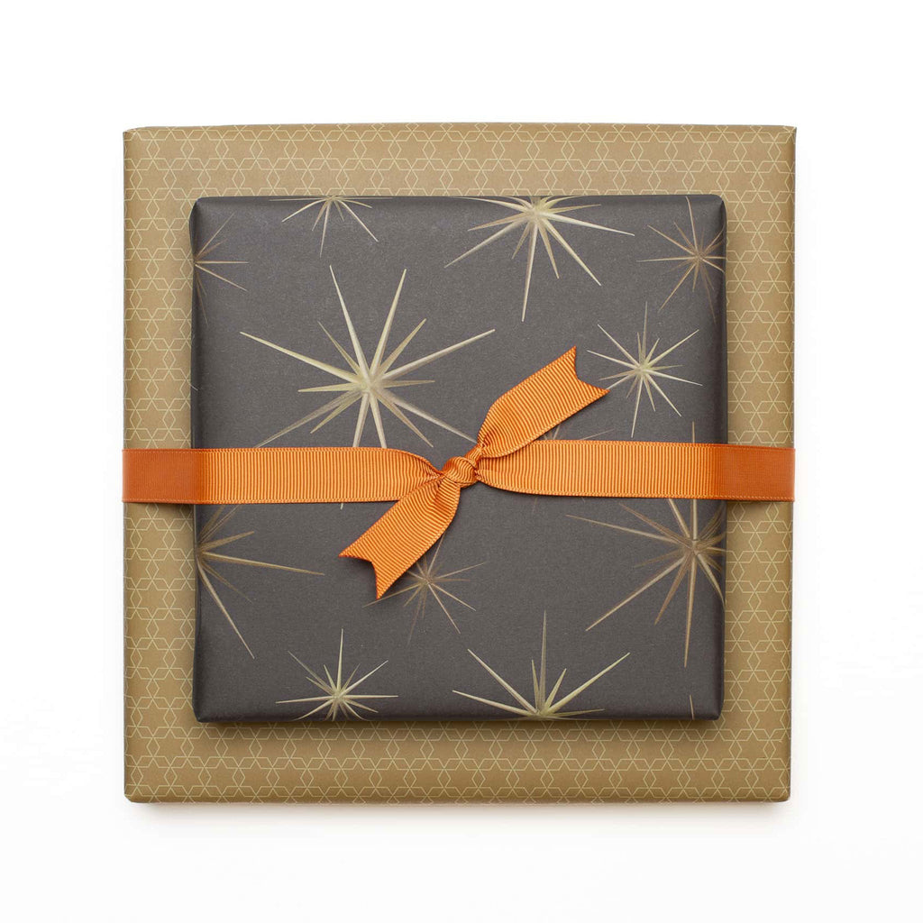 "Starburst" wrapping paper with golden yellow star ornaments against a brown background - printed on both sides on 100% recycled paper 