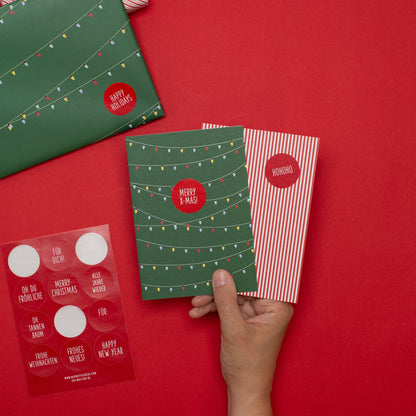 Karten mit Lichterkette auf Grün und rot-weißen Streifen, mit Grußstickern auf Deutsch, Umschlägen und Geschenk